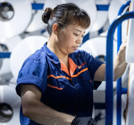 A worker operates automated spinning machinery at a textile factory in Huzhou, China, reflecting China's strong manufacturing growth in mid-2025.